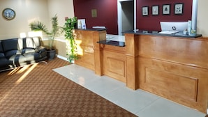 Una zona de recepción con un escritorio de madera, un reloj en la pared y una planta.