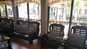 A room with a patterned tile floor, wooden furniture with cushioned seats, and large windows with curtains. - Tubod Flowing Waters Resort (Talisay)