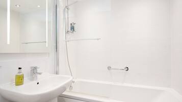 A modern bathroom with a white sink, a bathtub, and a glass shower enclosure.