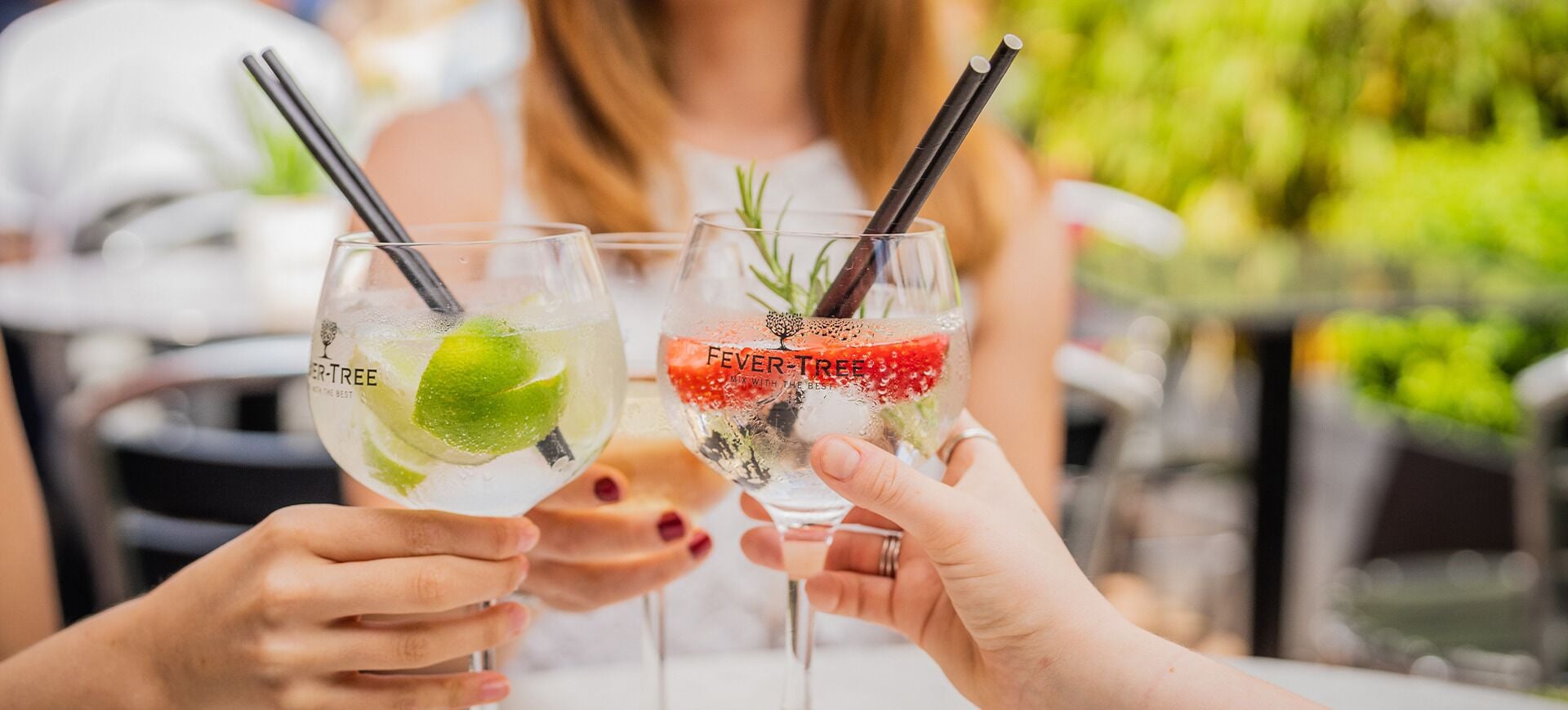 Two people holding glasses with a beverage and a garnish.
