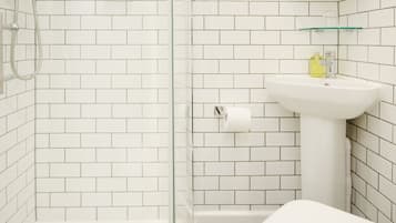 A bathroom with a glass-enclosed shower, a white sink, and a toilet.