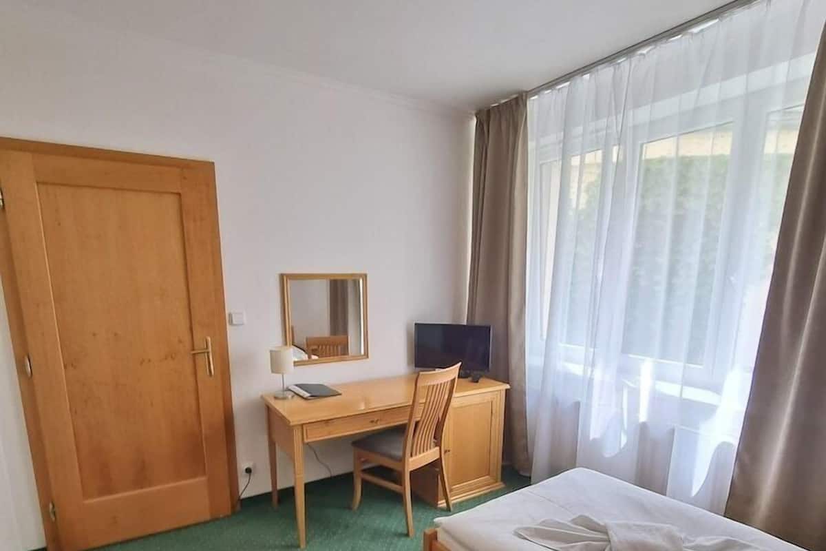 Une chambre d’hôtel équipée d’un lit, d’un bureau, d’une chaise, d’une télévision et d’une porte.