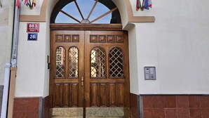 A hotel entrance with a large arched doorway, wooden double doors with glass panels, and a sign above indicating the address. - Hotel Claris (Prague)