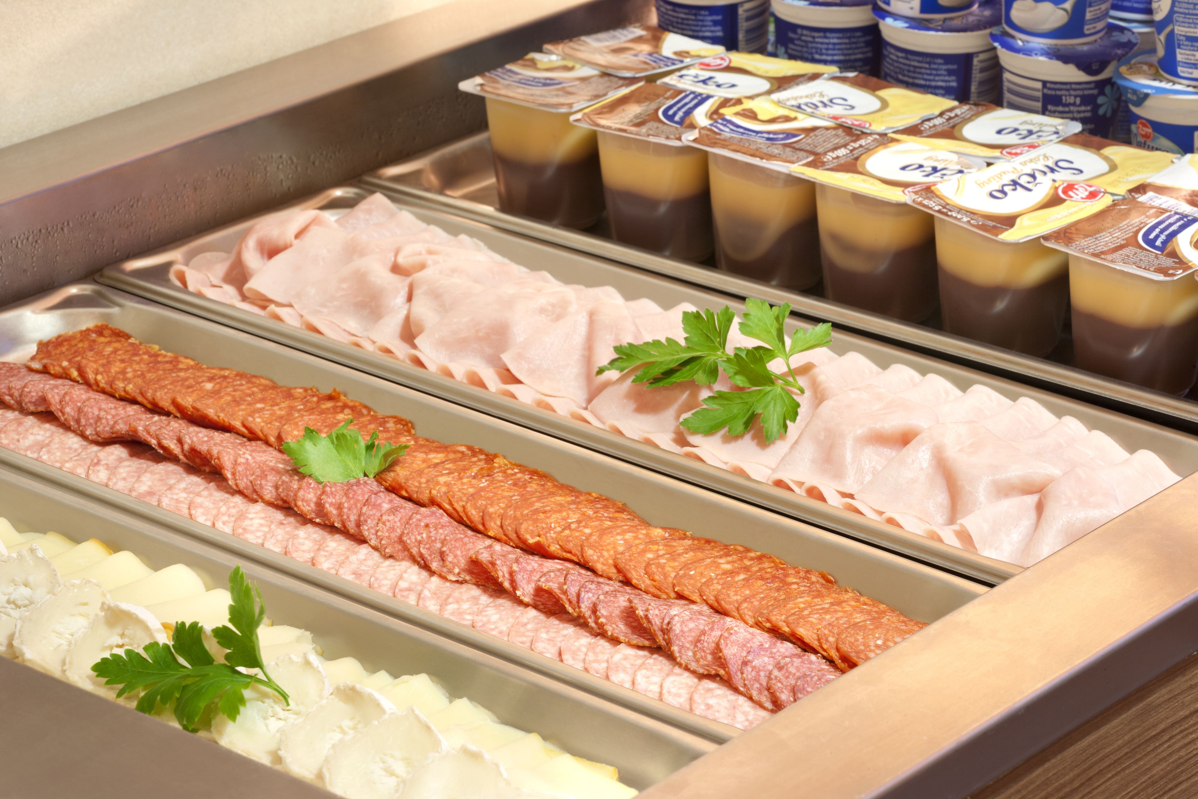 A buffet with various meats, cheeses, and dairy products.