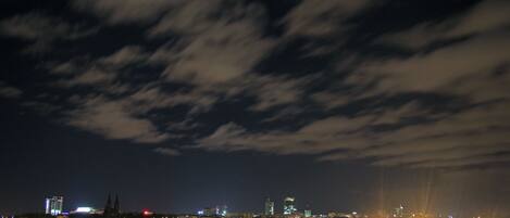 A nighttime cityscape with illuminated buildings and a cloudy sky.