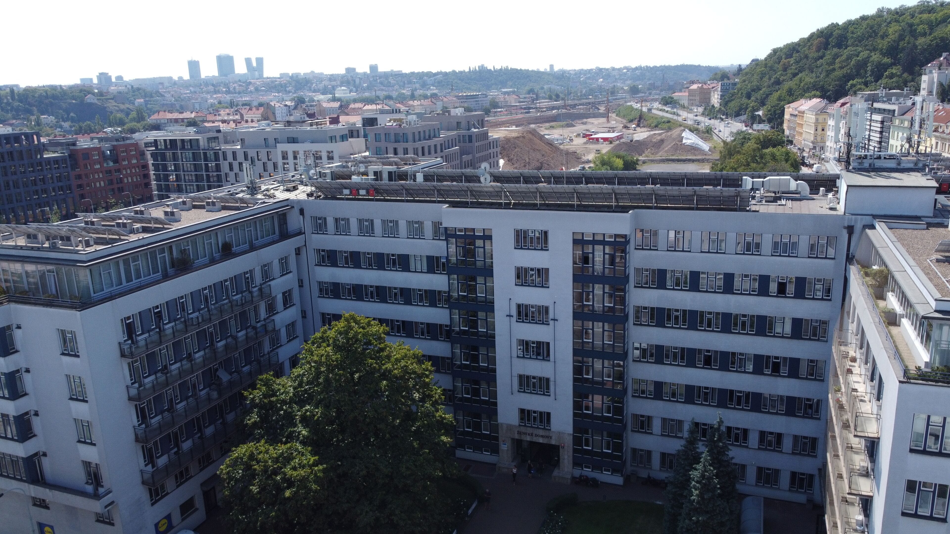 Un immeuble à plusieurs étages doté d’une architecture moderne, comprenant une cour intérieure et offrant une vue sur le paysage urbain environnant.
