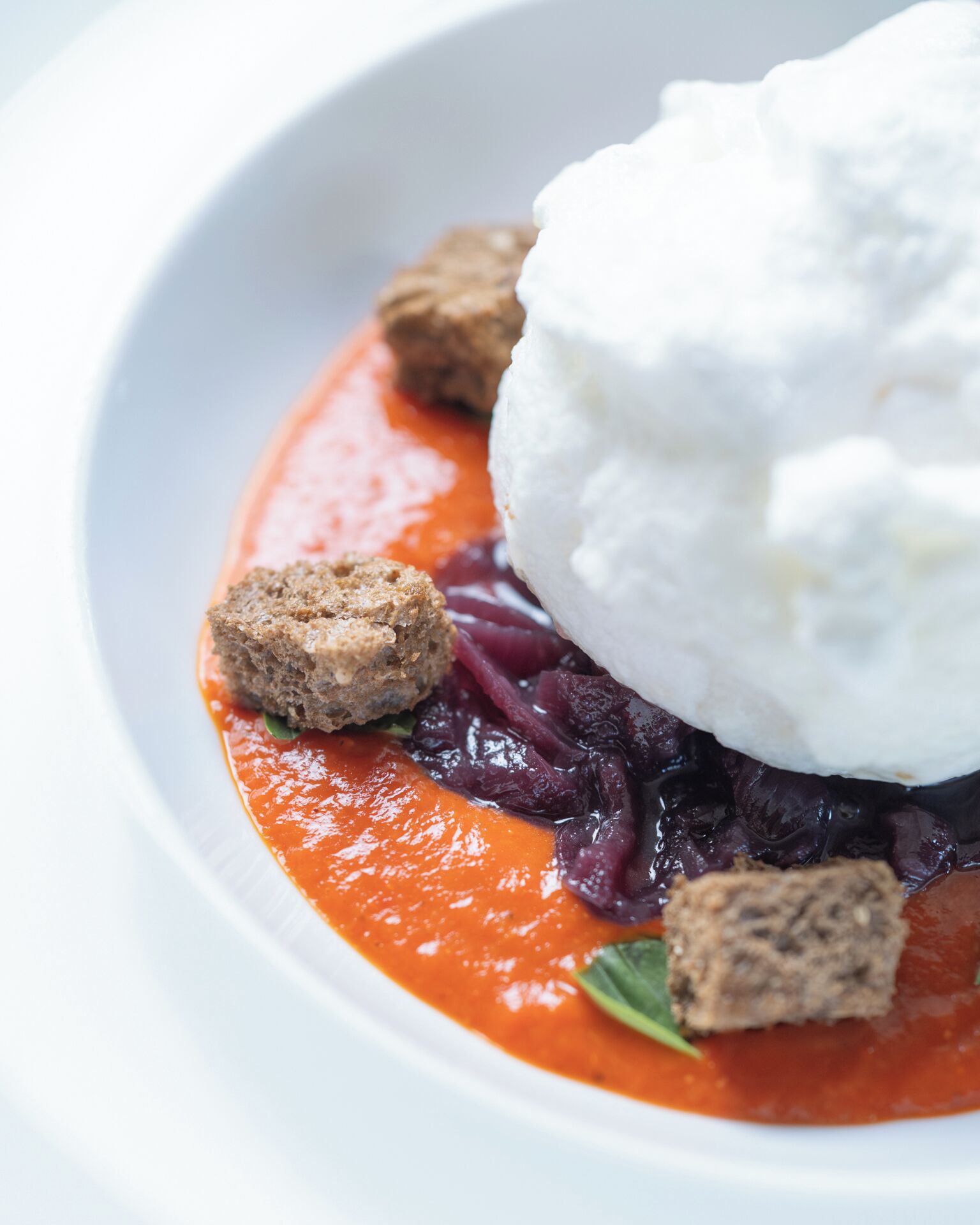 Un plato de postre con una bola de helado, un trozo de pastel y salsa roja.
