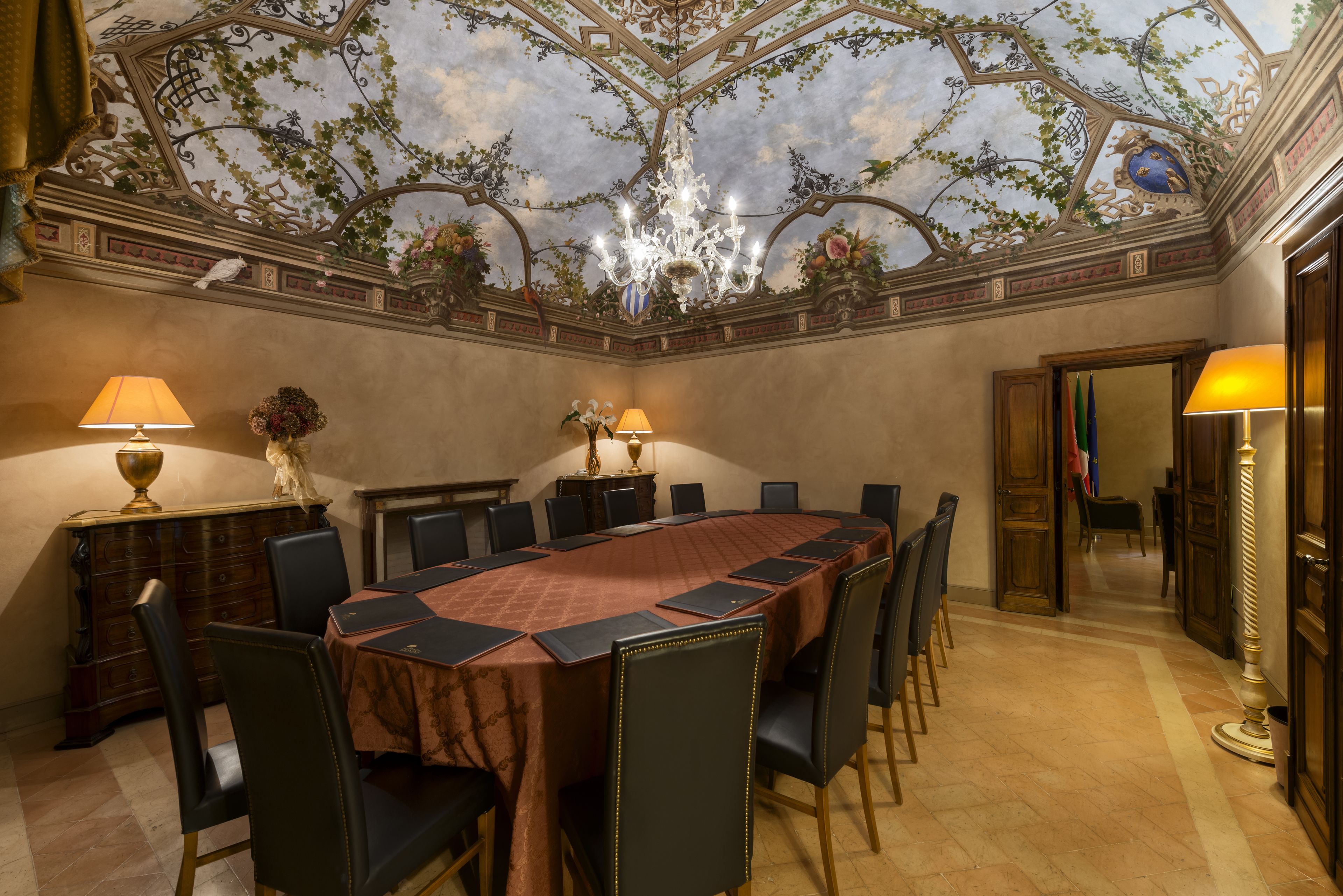 A conference room with a large oval table, chairs, and lamps.