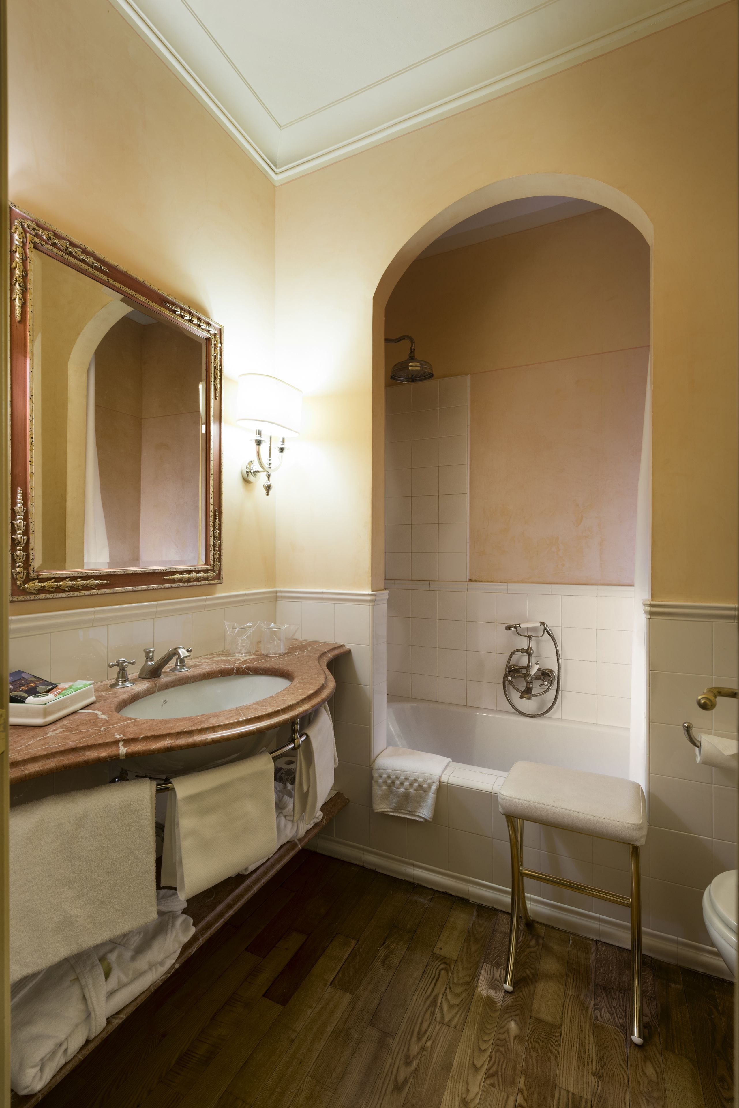 A bathroom with a marble sink, a large mirror, a shower, and a toilet.