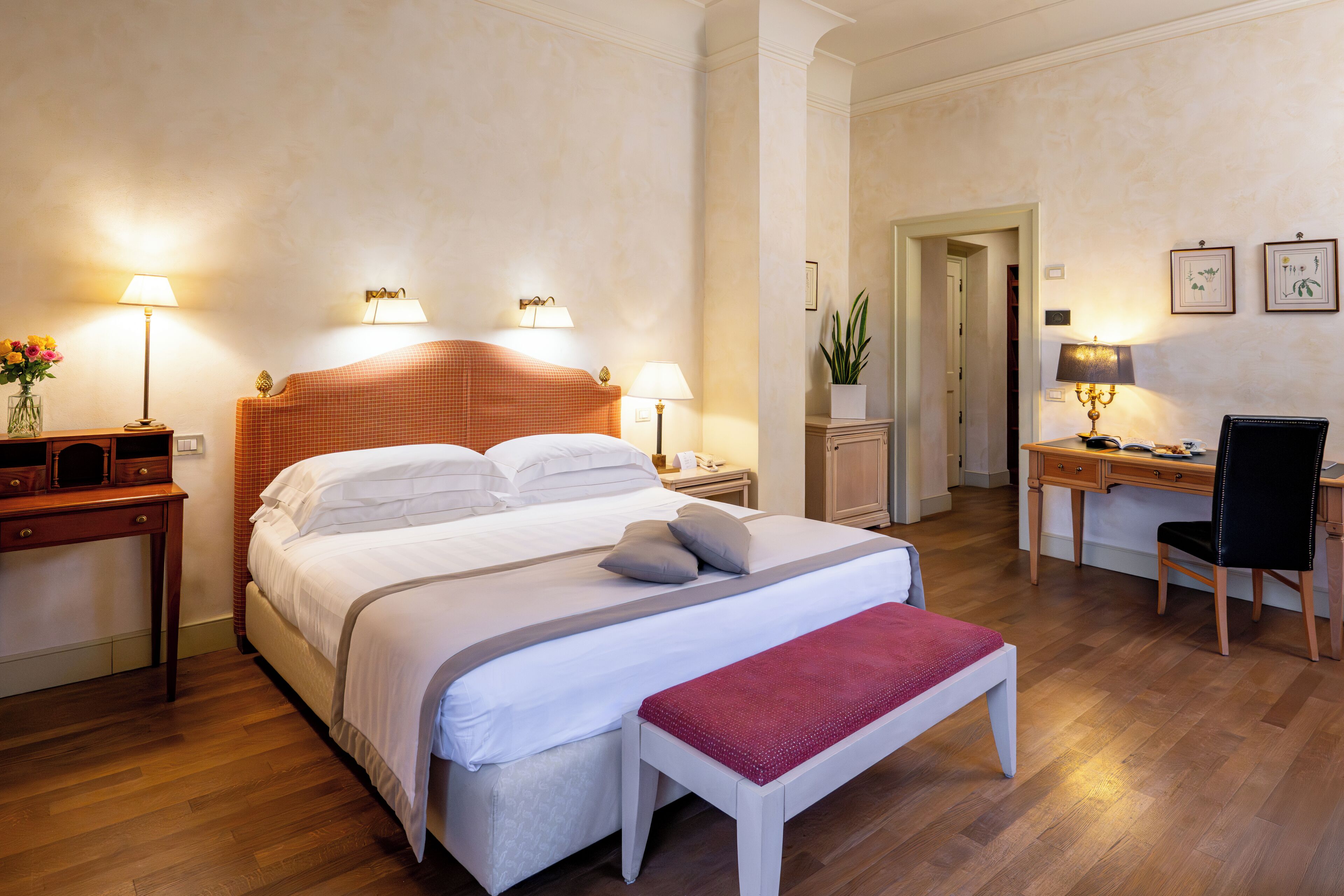 Una habitación de hotel con una cama grande, mesitas de noche, un escritorio y una silla.