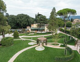 Un jardín ajardinado con un pabellón, una fuente y setos bien recortados.