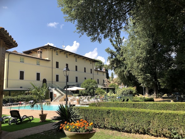 A building with a pool, outdoor seating, and a well-maintained garden.