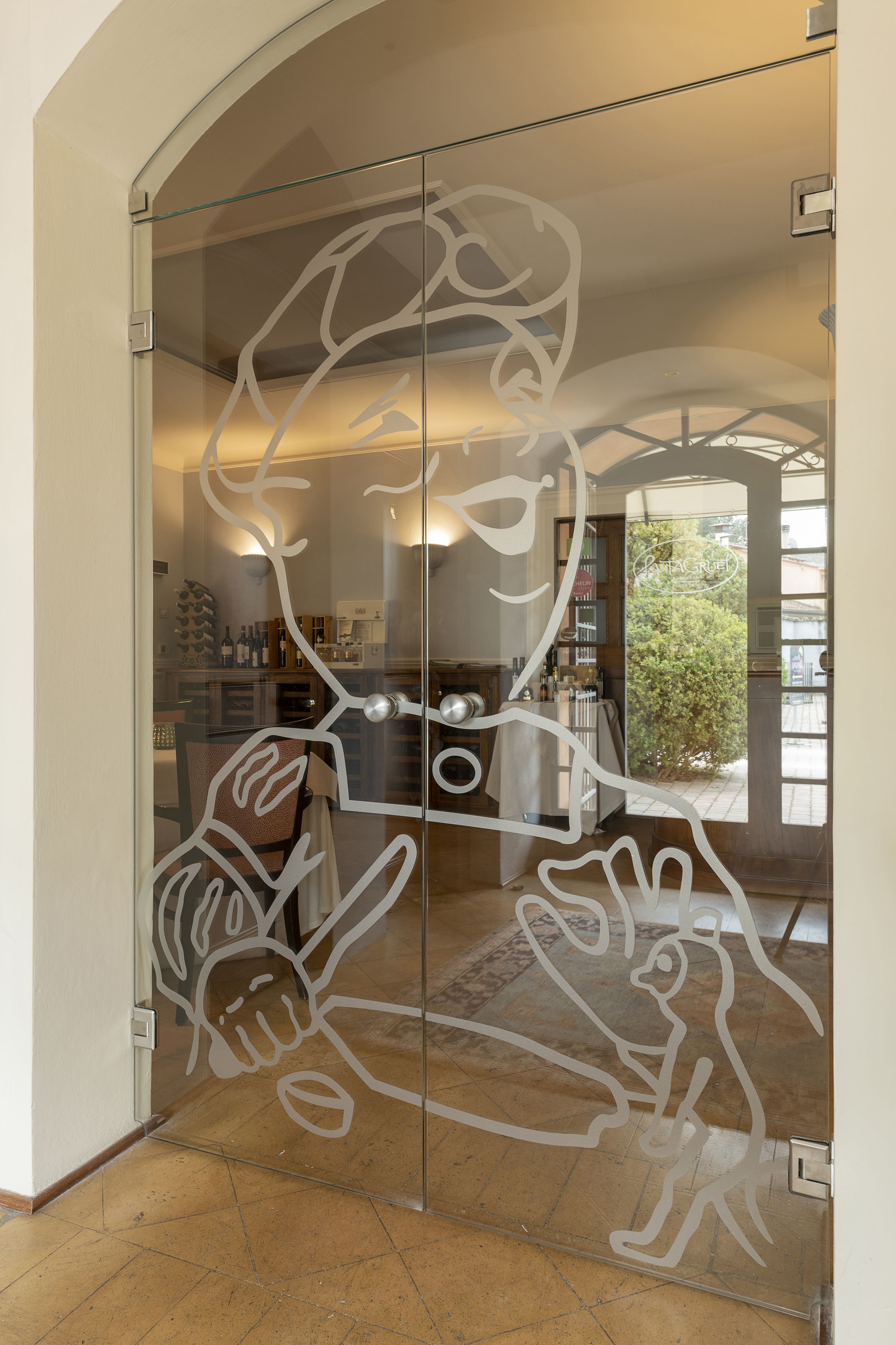 Une porte en verre ornée d’un motif abstrait blanc.