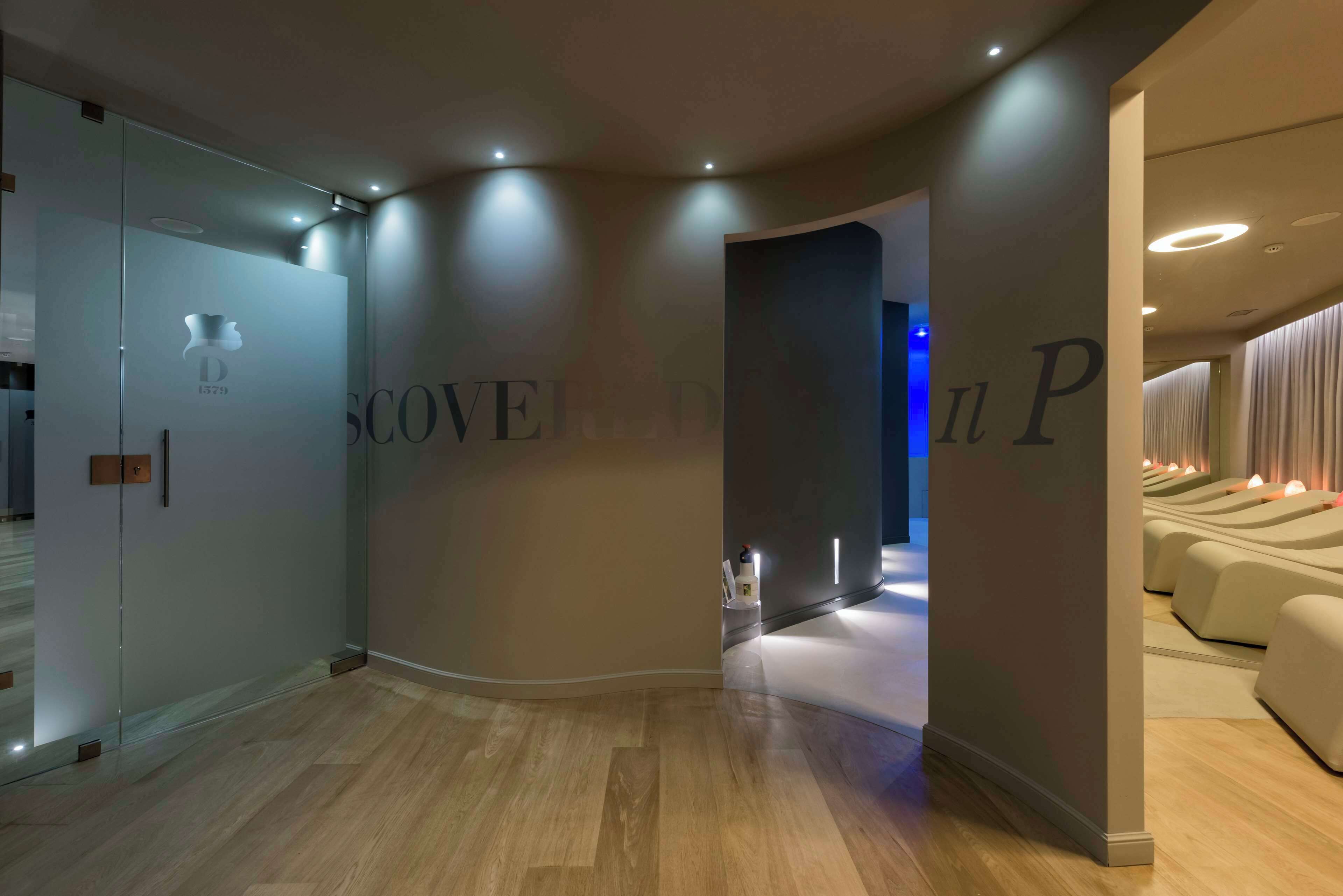 Ein modernes Hotel-Interieur mit einer geschwungenen Wandgestaltung, einer Rezeption und einem Massageraum.