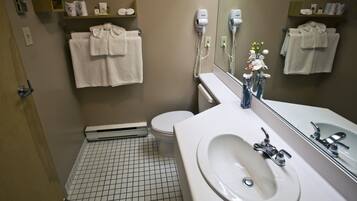 Une salle de bain avec un lavabo blanc, un miroir, des toilettes et un porte-serviettes.
