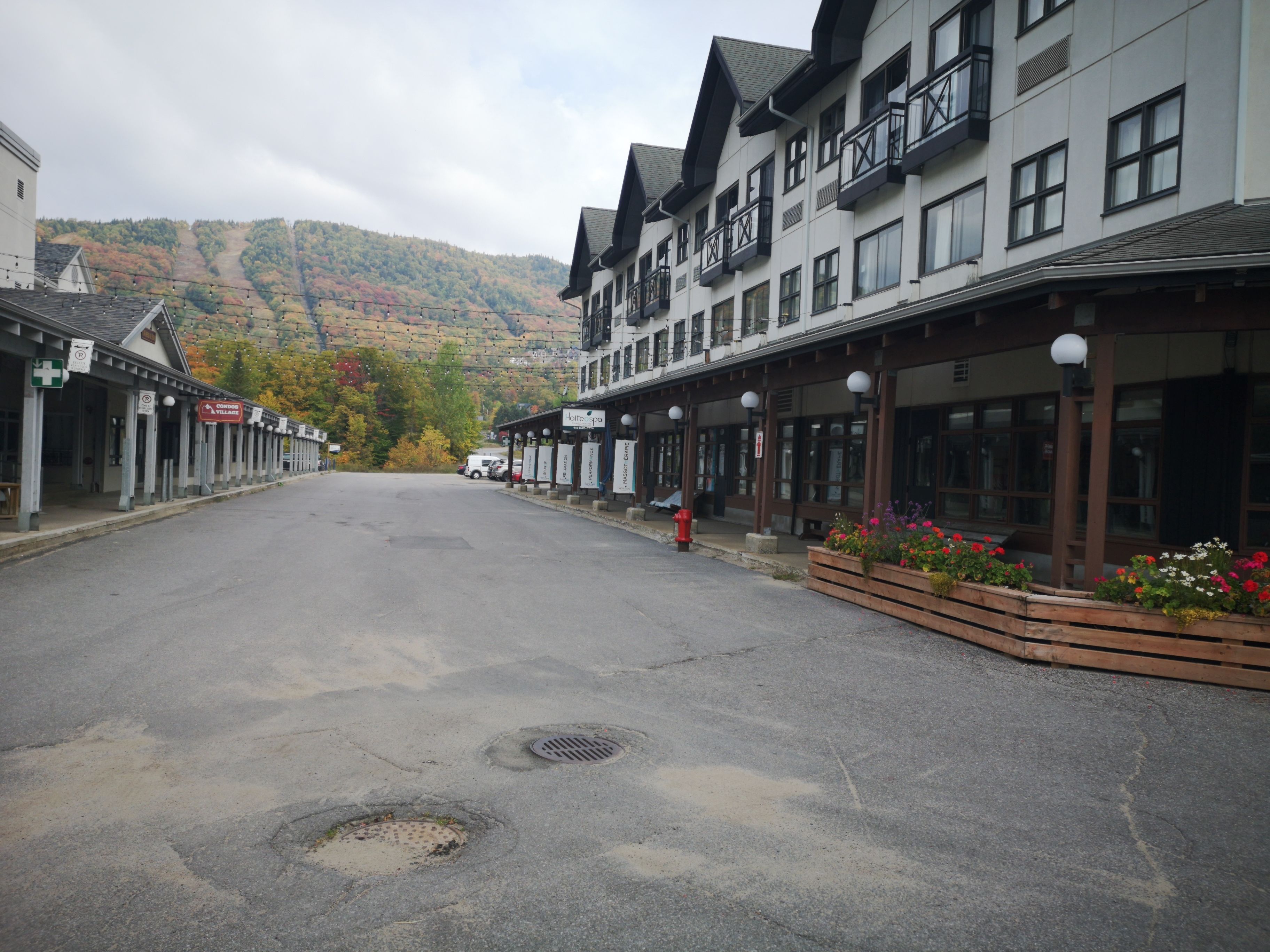 A street with buildings on either side, a clear sky, and a mountain in the background.