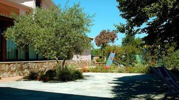 Enjoy the serene outdoor space with a paved patio, a tree, and a playground nearby.