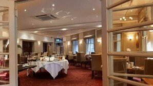 A hotel room with a large bed, a desk, and a chair. There is a window with a view of the city. - The Lismoyne Hotel (Fleet)