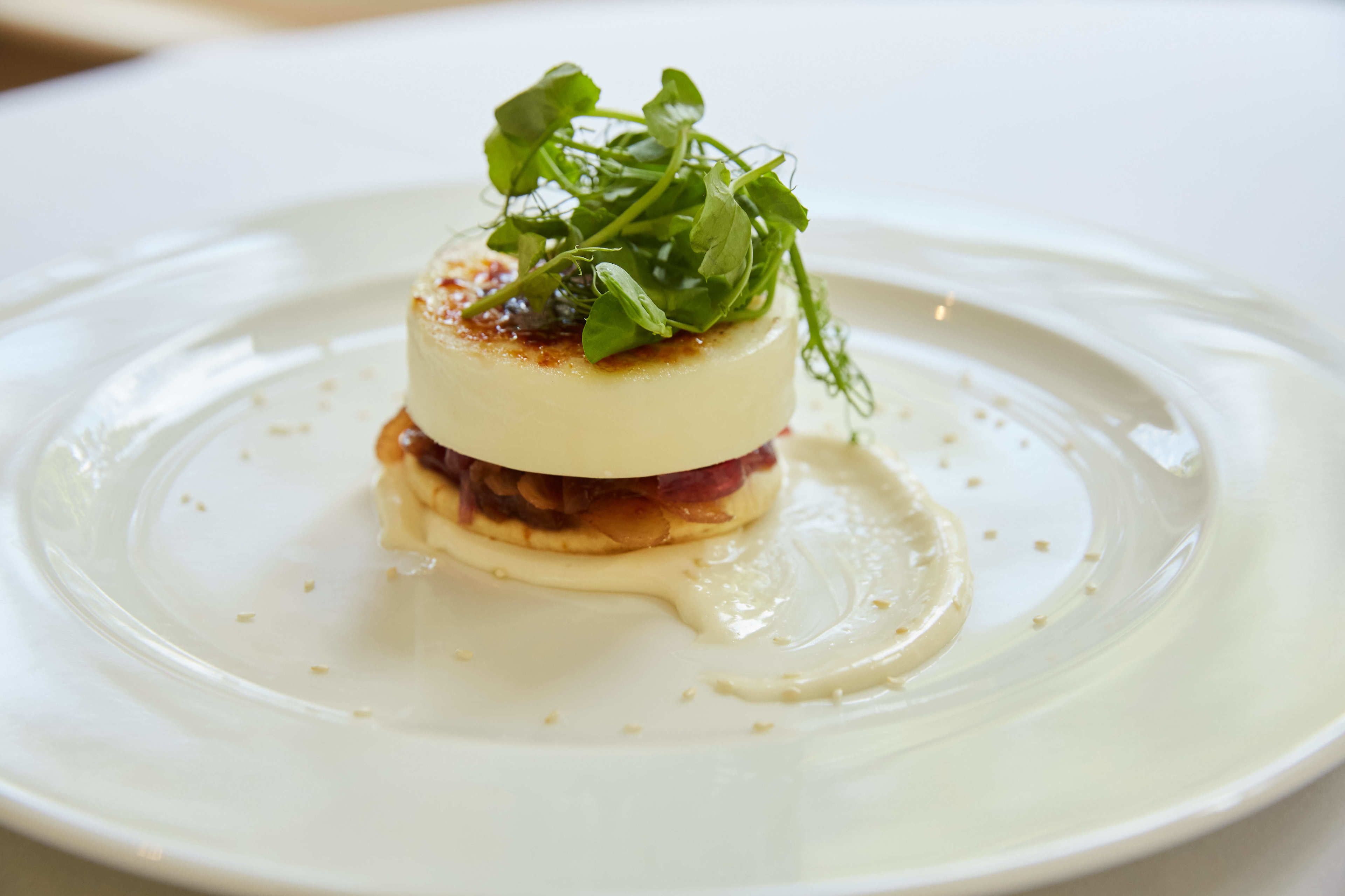 A white plate with a layered food item, garnished with green leaves.