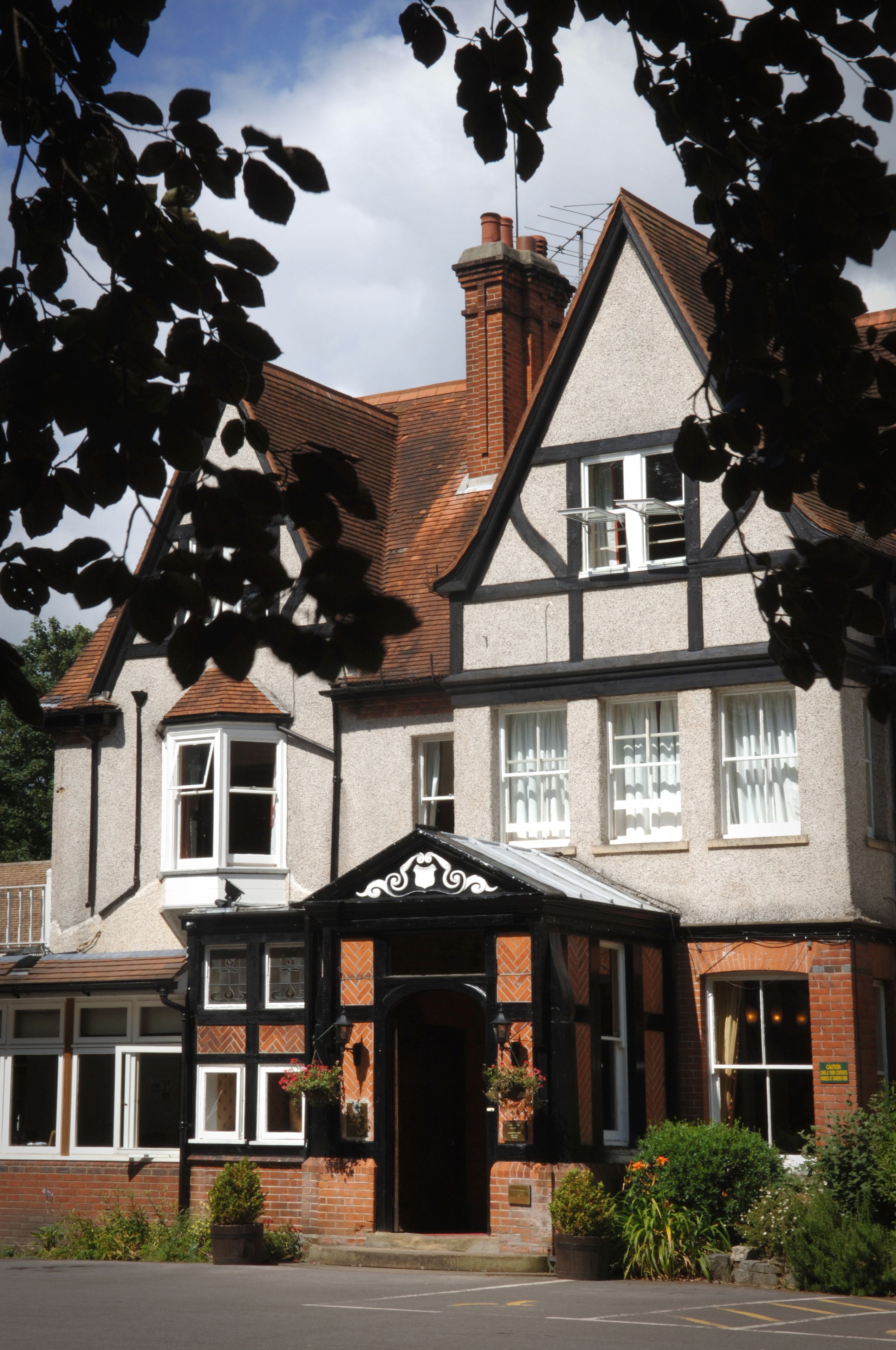 A traditional building with a prominent entrance, multiple windows, and a brick chimney.