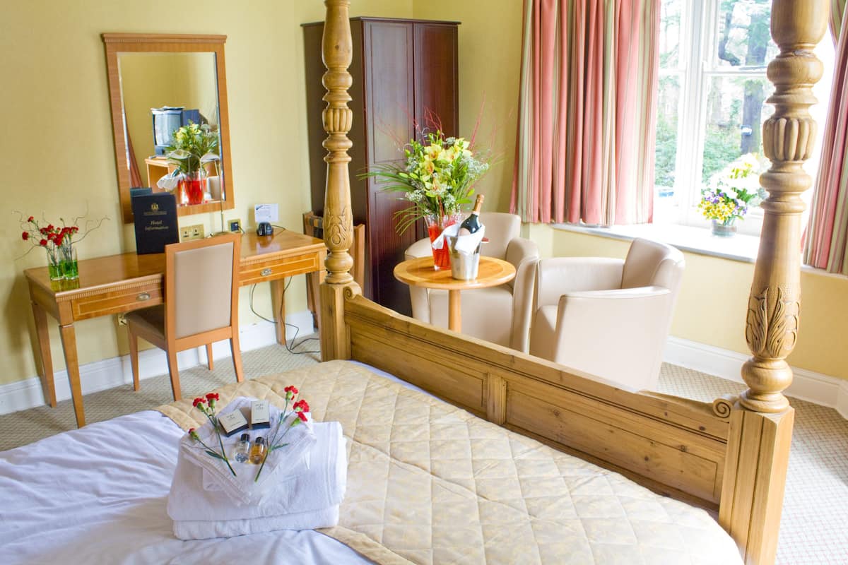 A hotel room with a bed, a desk, a chair, a wardrobe, and a window with curtains.