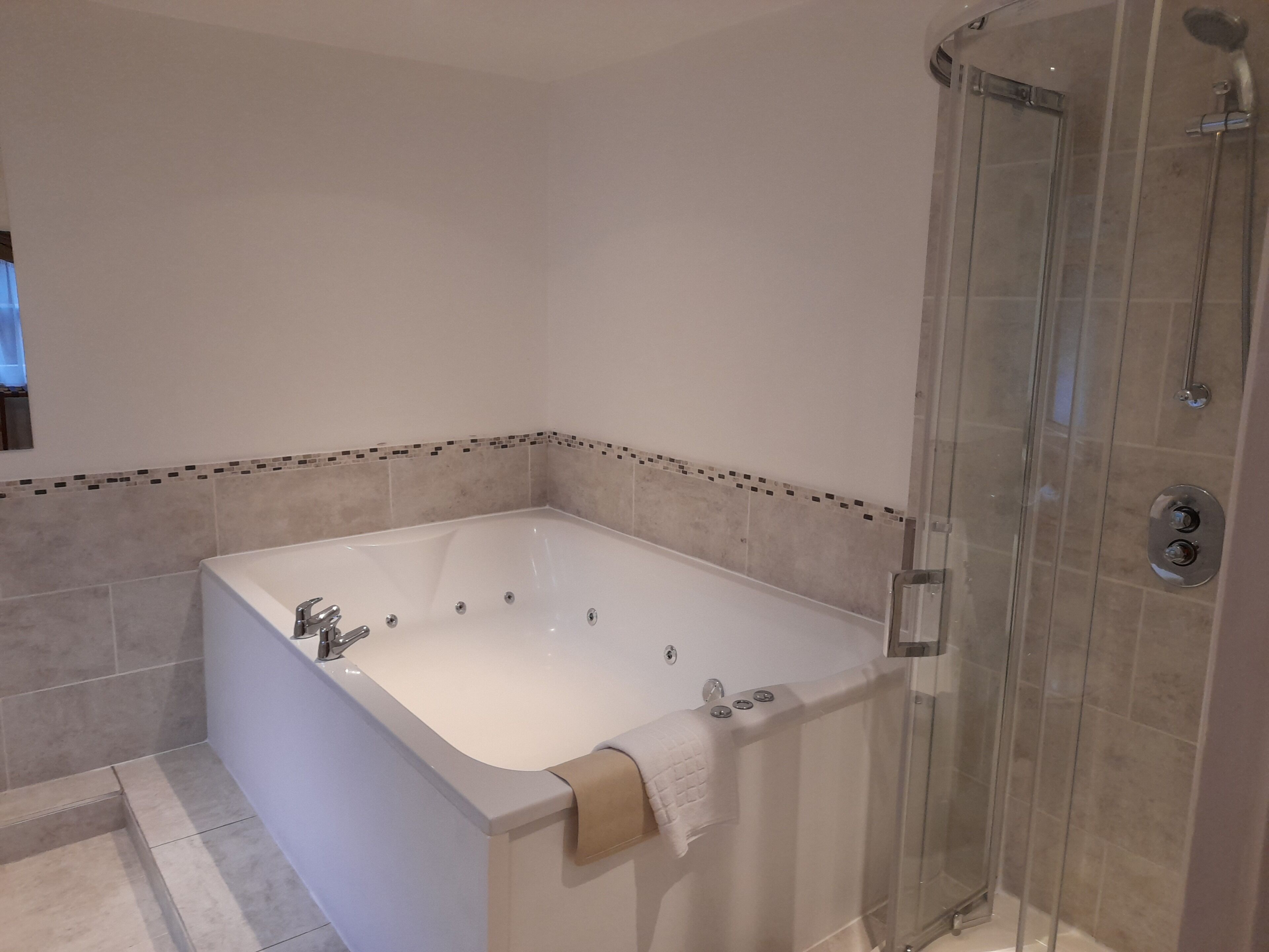 A modern bathroom with a freestanding bathtub, a glass-enclosed shower, and a tiled floor.