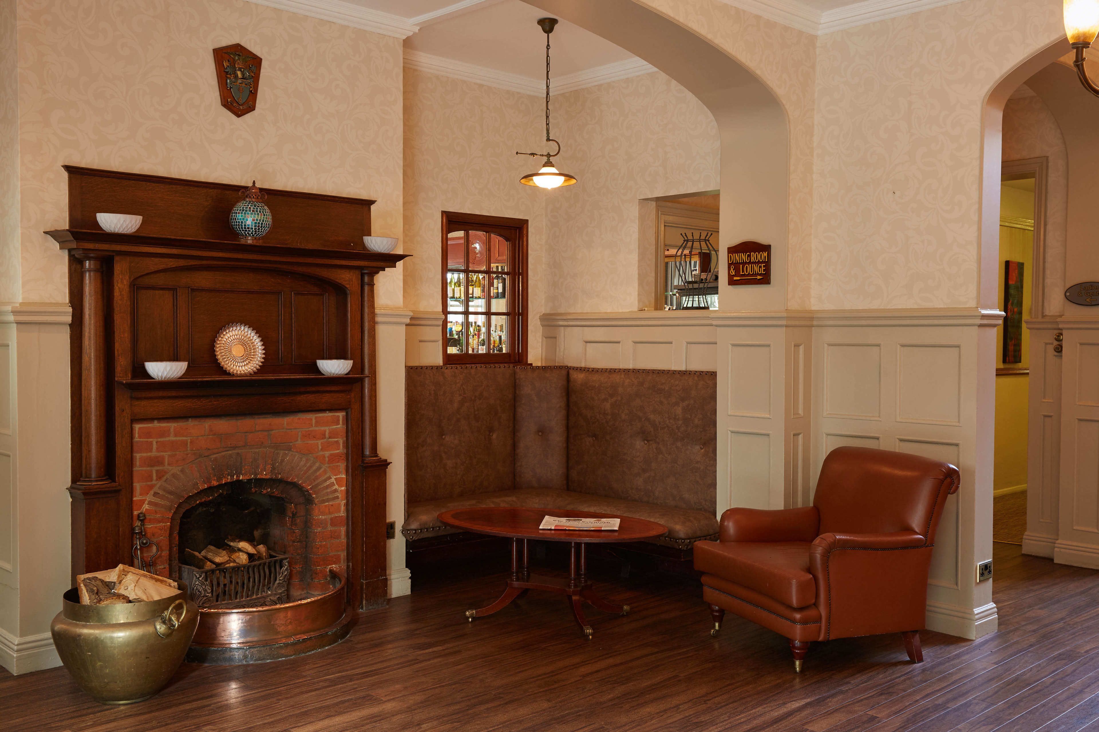 A room with a fireplace, a bench, a table, and a leather armchair.