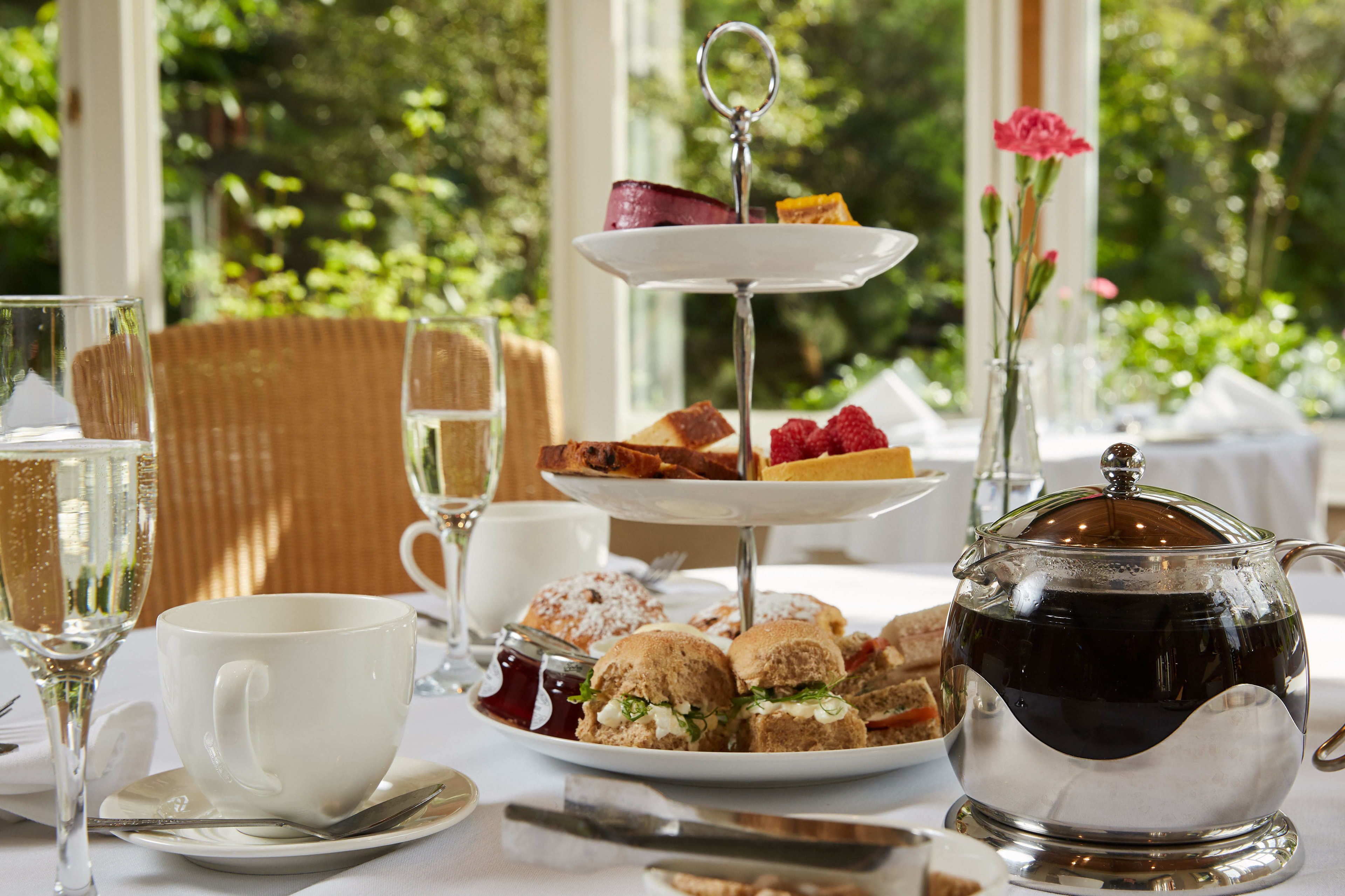 A table set for a tea service with a teapot, cups, and a tiered dessert stand.