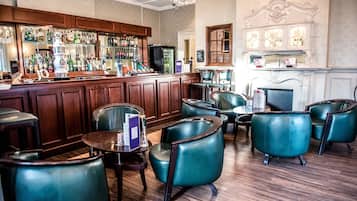 A bar area with wooden cabinets, a variety of bottles, and teal leather chairs.