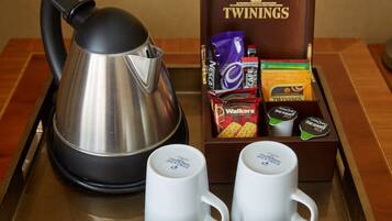 Una bandeja con una tetera, dos tazas de café y una caja de té Twinings.