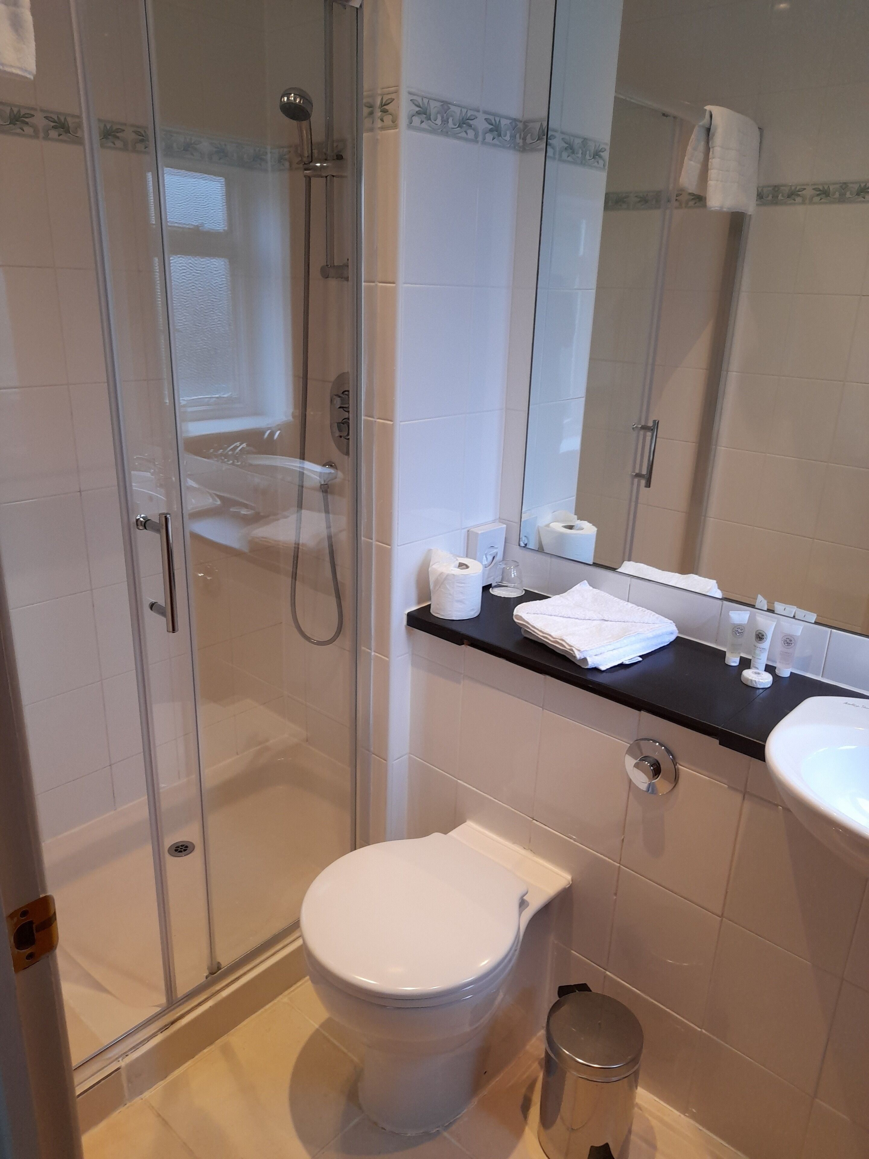 Un baño moderno con cabina de ducha de vidrio, inodoro, lavabo y espejo.