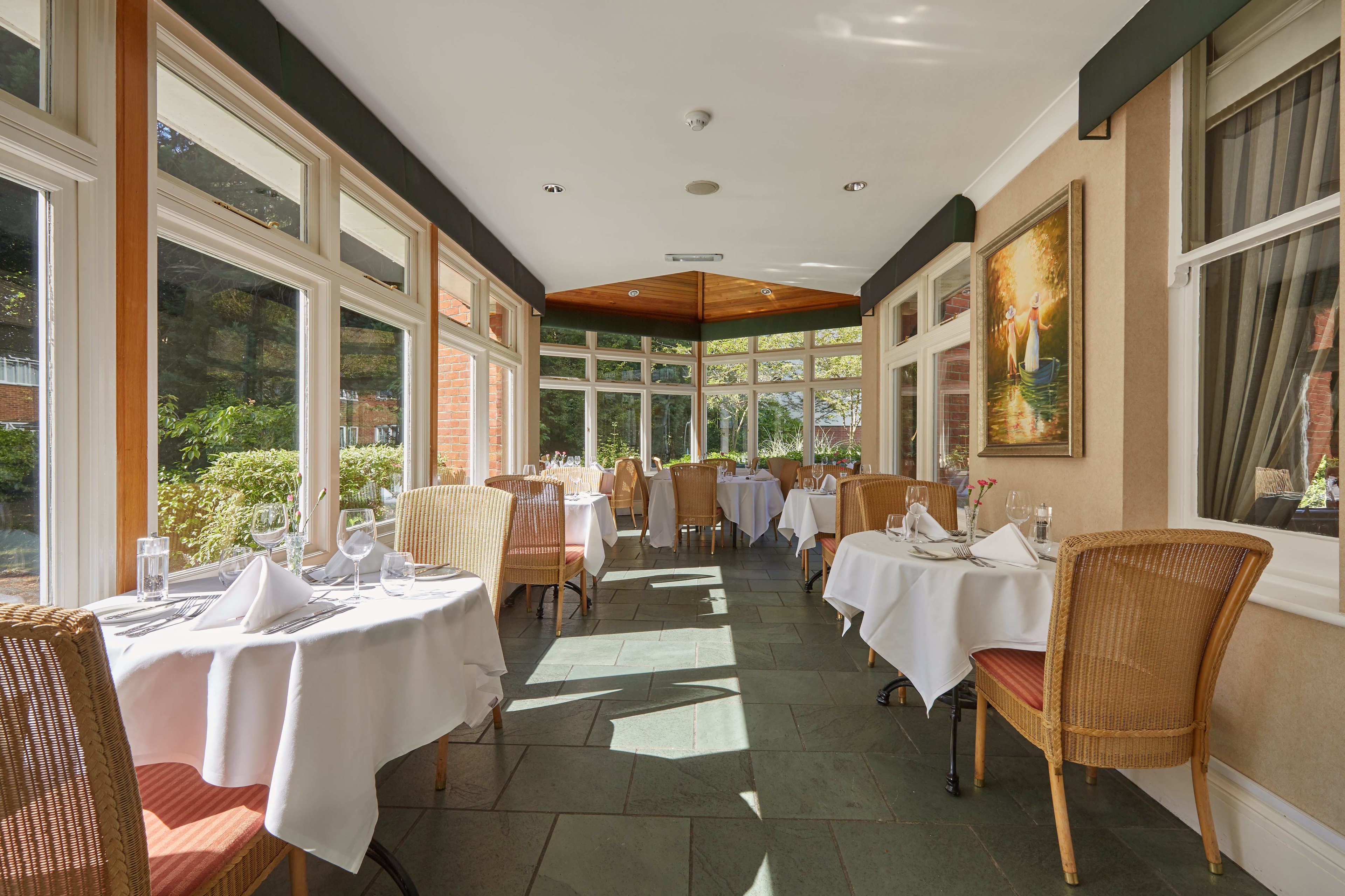 A restaurant with multiple tables and chairs, large windows, and a ceiling fan.
