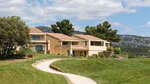 A two-story house with a curved driveway, surrounded by well-maintained grass and trees.