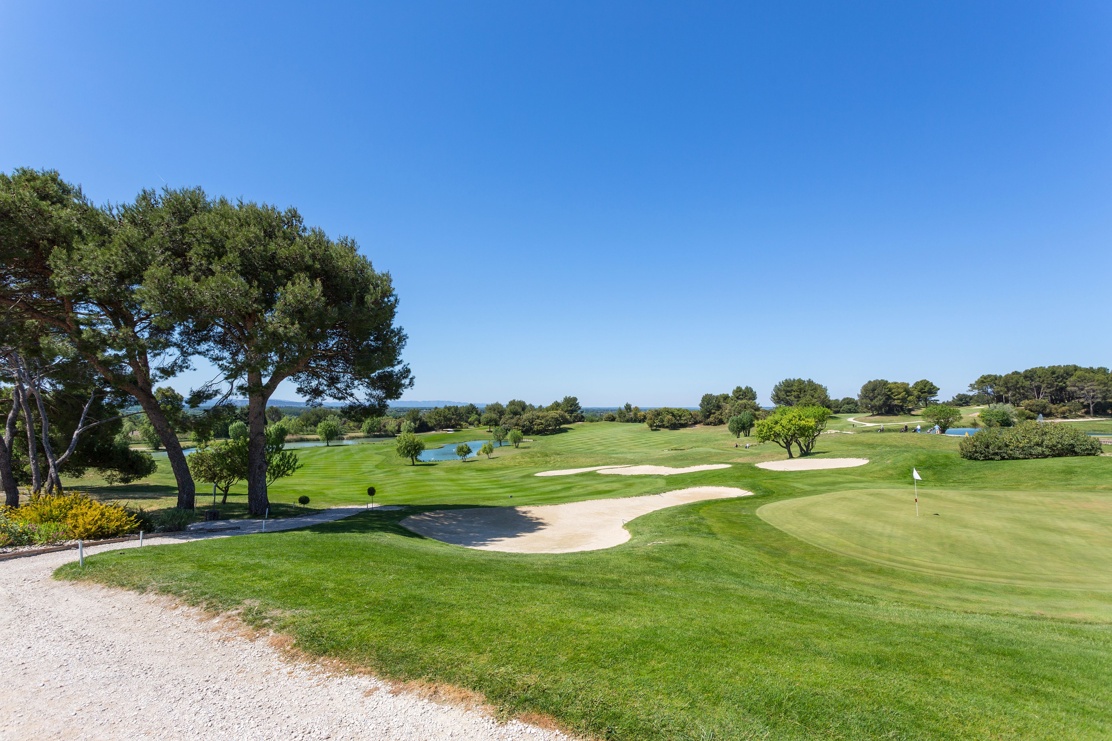 Ein Golfplatz mit Sandbunkern, Bäumen und blauem Himmel.