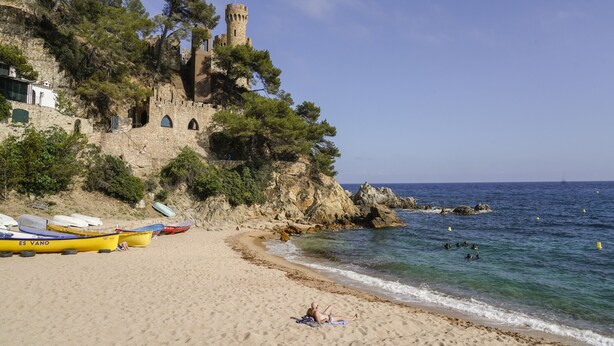 A beach with boats, a castle, and rocky cliffs. - Lloret Vibe Affiliated by FERGUS (Lloret de Mar)