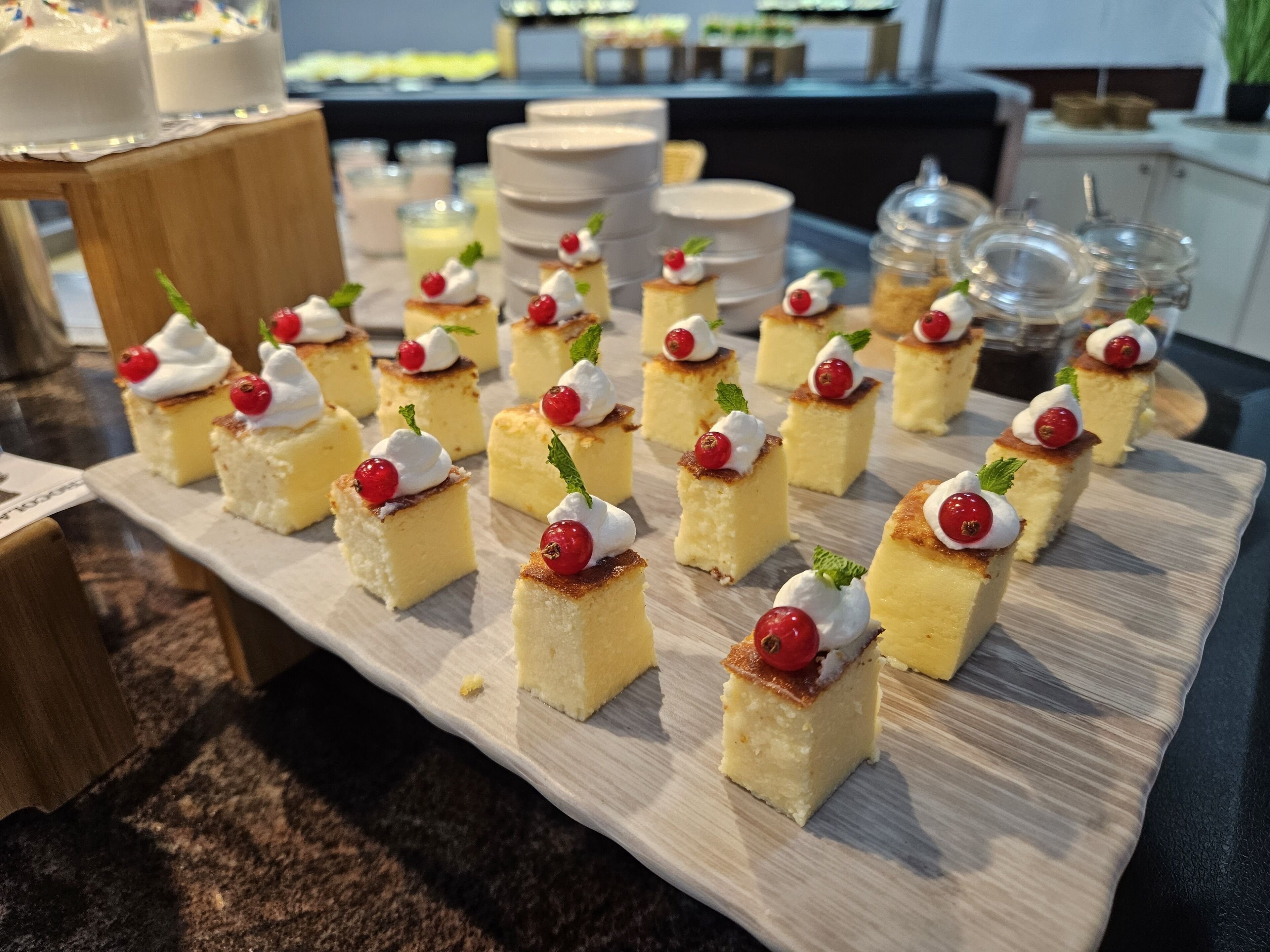 Una bandeja de postres con pequeños bizcochos cubiertos de crema batida y frutos rojos.