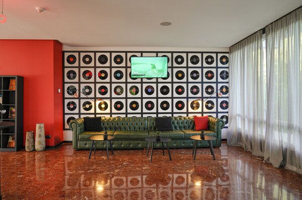 A living room with a green sofa, two coffee tables, and a wall of vinyl records.