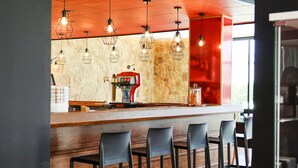 A bar area with a stone wall, wooden counter, and black bar stools. - Lloret Vibe Affiliated by FERGUS (Lloret de Mar)
