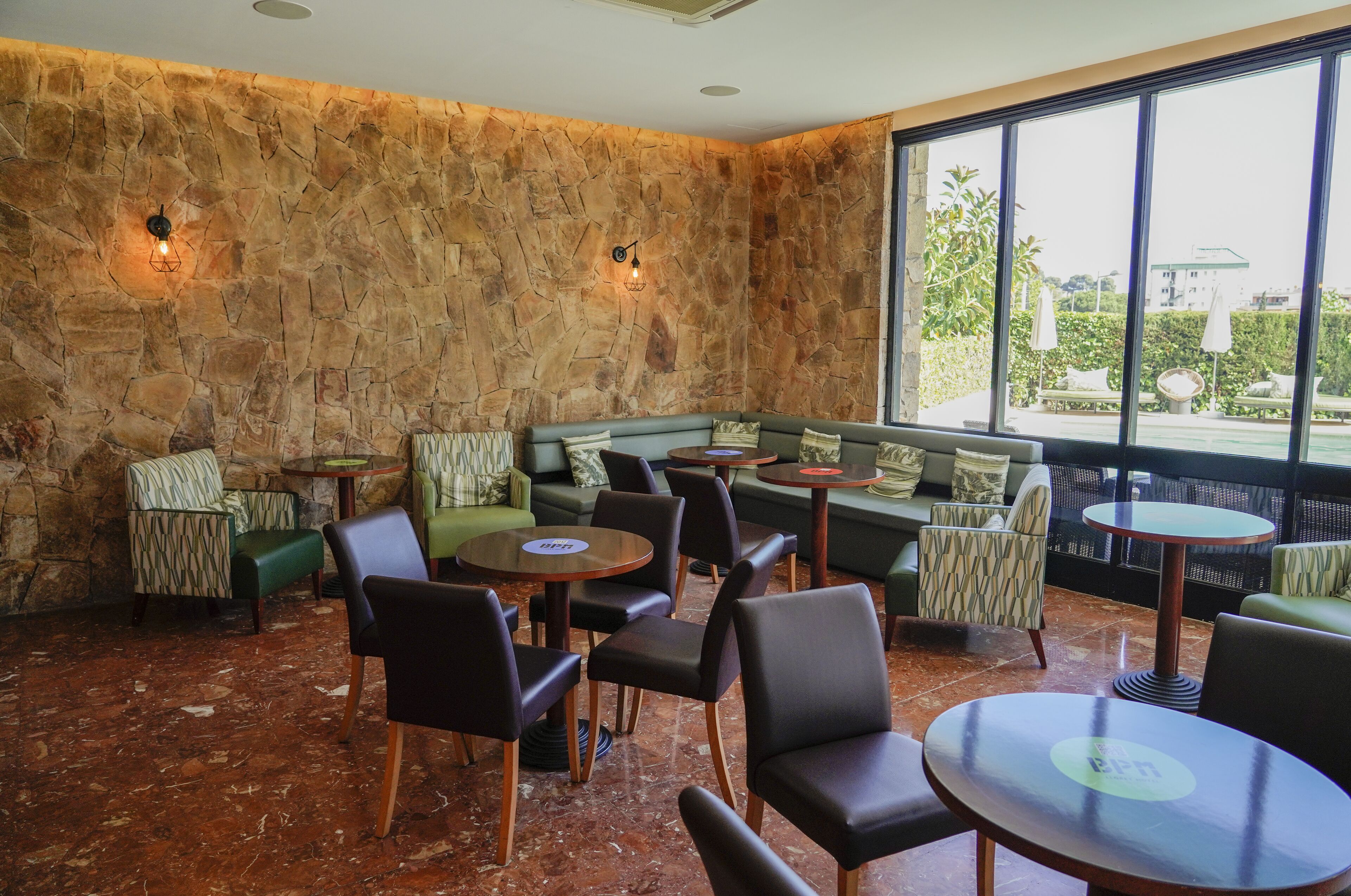 A cozy lounge area with stone walls, comfortable seating, and a view of the outdoors.