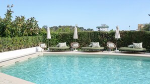 A pool with lounge chairs and umbrellas, surrounded by greenery and buildings in the background. - Lloret Vibe Affiliated by FERGUS (Lloret de Mar)