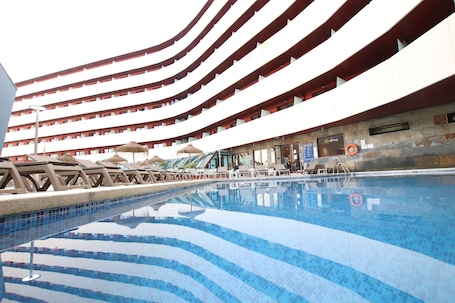 Una piscina al aire libre de temporada, sombrillas, tumbonas
