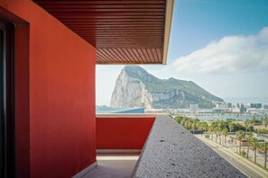 Un balcon offrant une vue sur une montagne et sur le paysage urbain.
