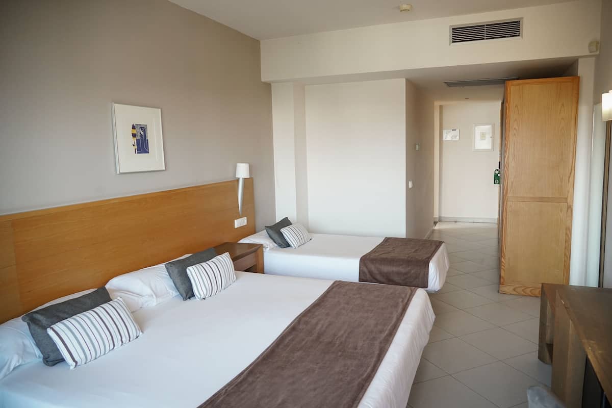 A hotel room with two beds, a wooden headboard, a framed picture on the wall, and a wooden door.