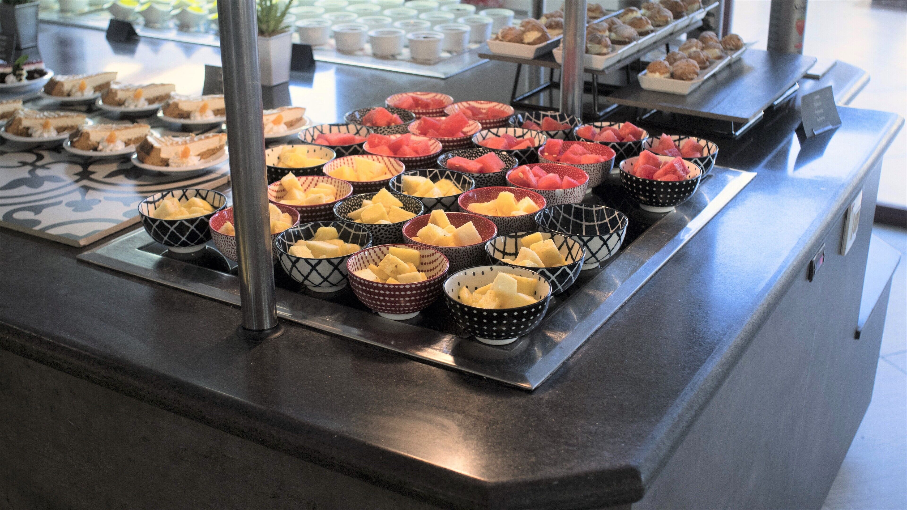 A buffet with various fruits and desserts arranged in bowls.