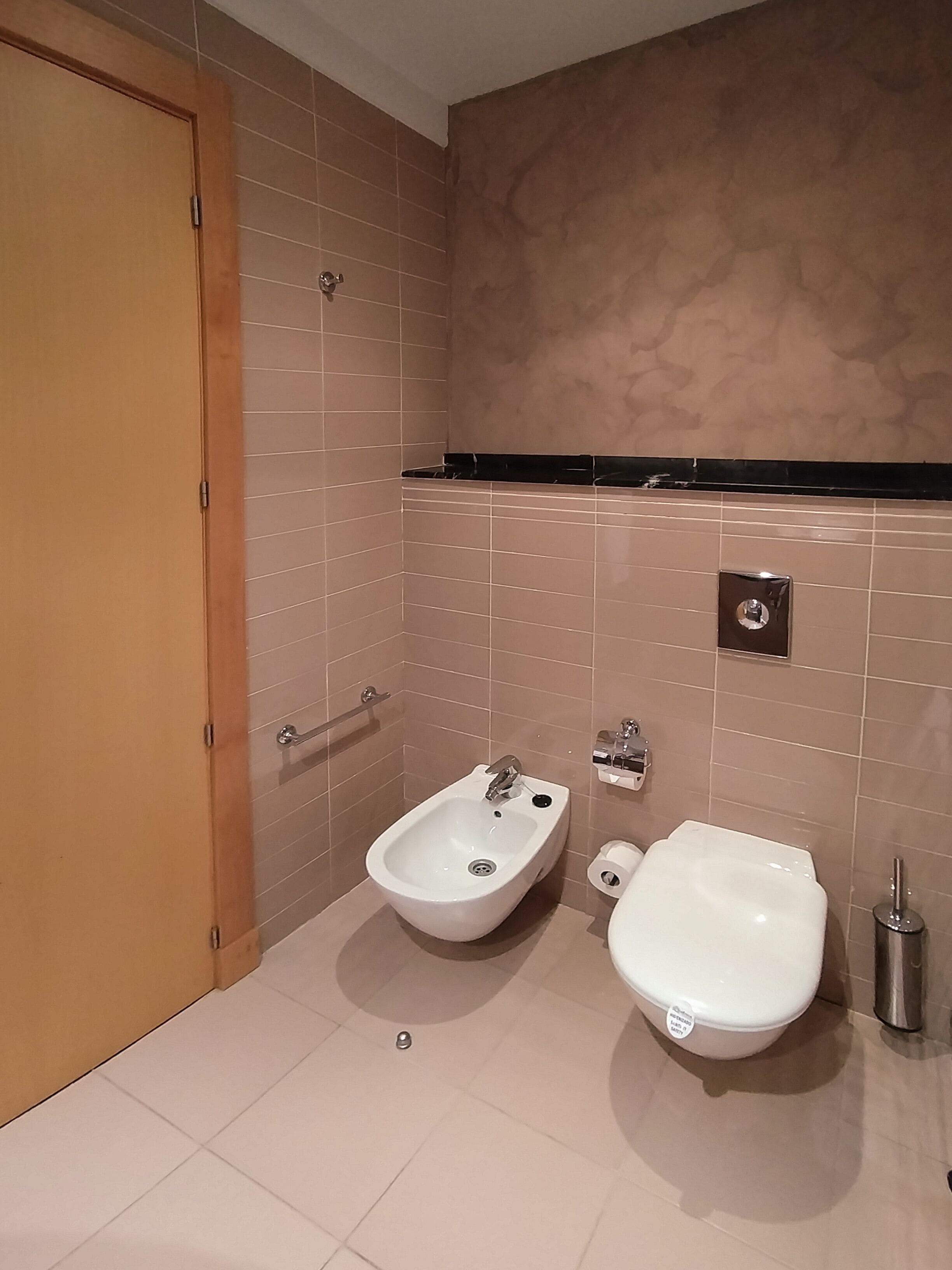 Et badeværelse med to vaske, et toilet og en skraldespand.