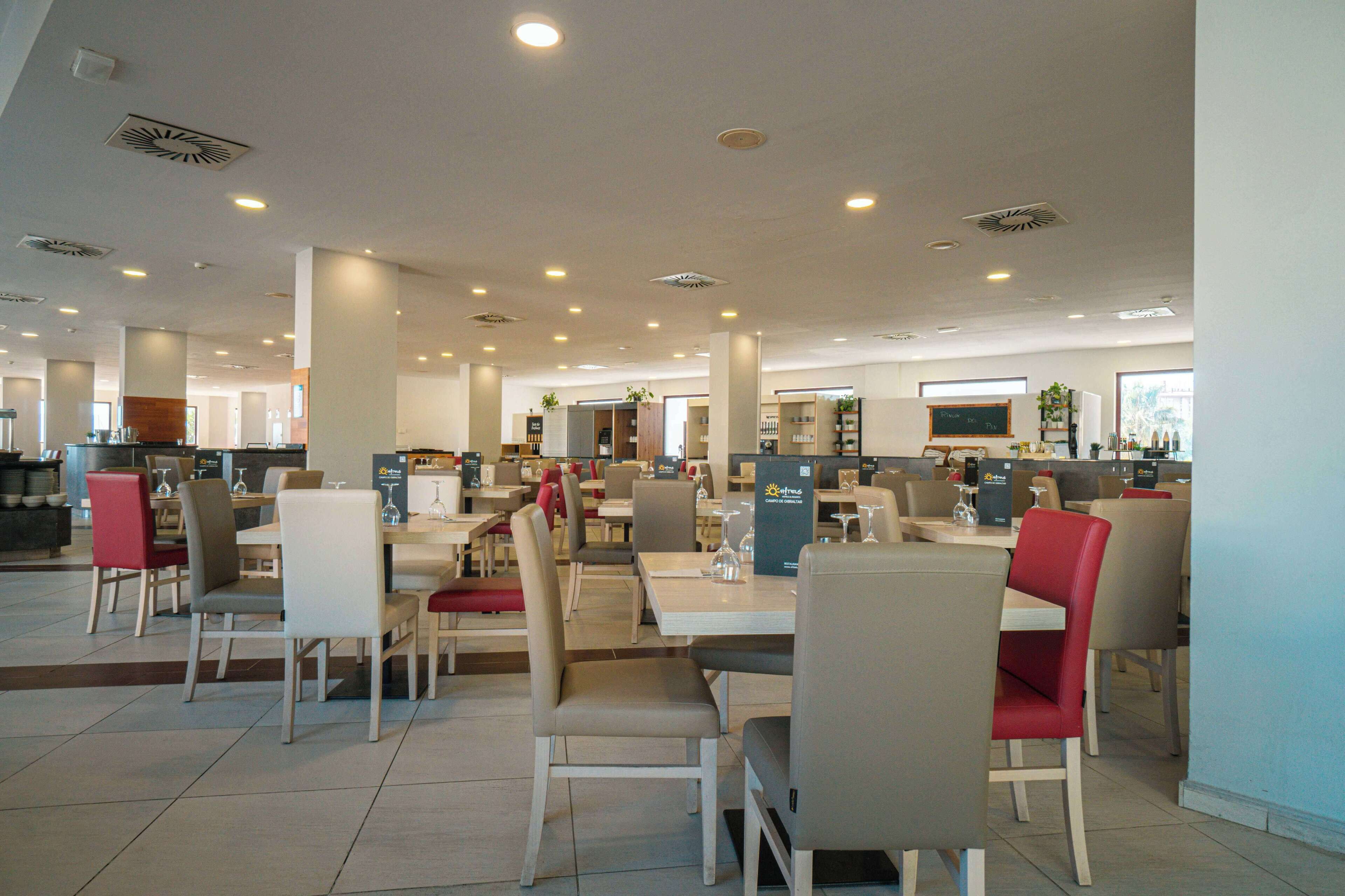 Un restaurante espacioso con varias zonas de comedor, techos altos y una decoración moderna.