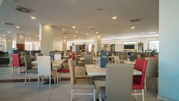 Un restaurante espacioso con varias zonas de comedor, techos altos y una decoración moderna.