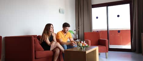Una sala de estar moderna con un sofá rojo, una mesa de centro y un ventanal con cortinas.