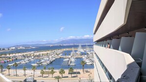 Ein Yachthafen mit vertäuten Booten, Palmen und freiem Blick auf den Hafen und die entfernten Berge.