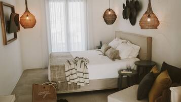Un dormitorio con cama, mesitas de noche, un sofá y lámparas colgantes.